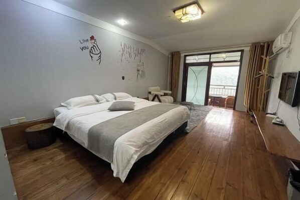 Een slaapkamer met een groot bed, houten vloeren, een raam met gordijnen en een muur met een tekening.