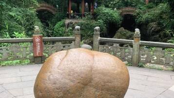 A large spherical sculpture in a garden with a traditional Chinese pavilion in the background.