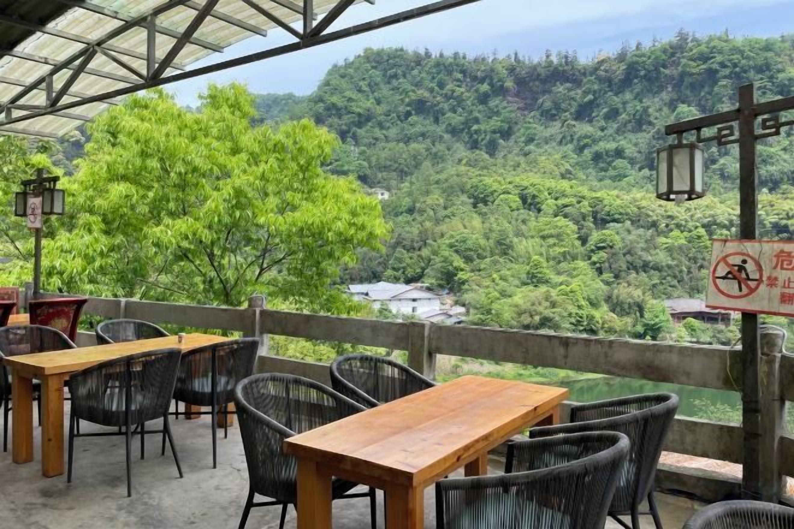 An outdoor seating area with tables and chairs, overlooking a forested valley.