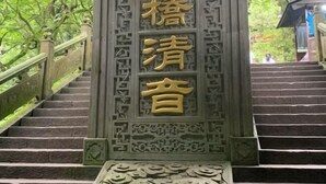 Een trap met sierlijk houtsnijwerk en een bord met Chinese karakters.