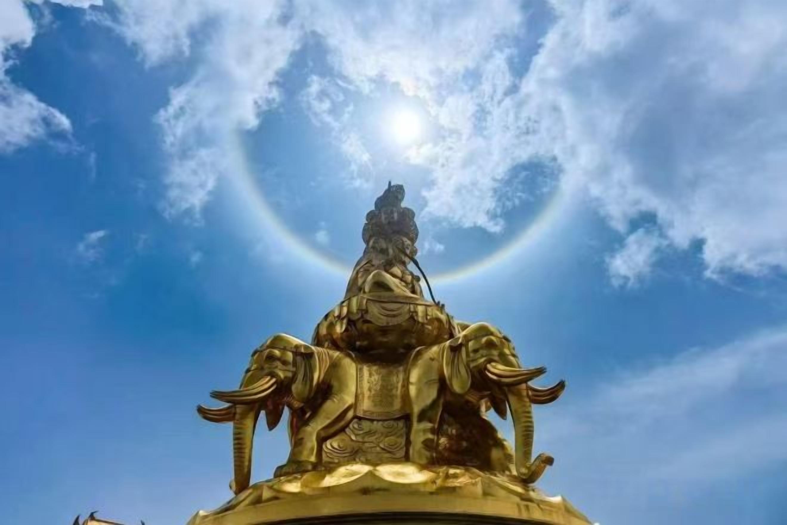 Une statue dorée représentant une figure assise sur un cheval, se détachant sur un ciel bleu clair.