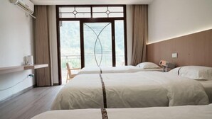 Een hotelkamer met twee bedden, een raam met uitzicht, een nachtkastje en een wandairconditioner.