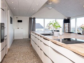 A modern kitchen with a large island, built-in appliances, and a view through the windows.