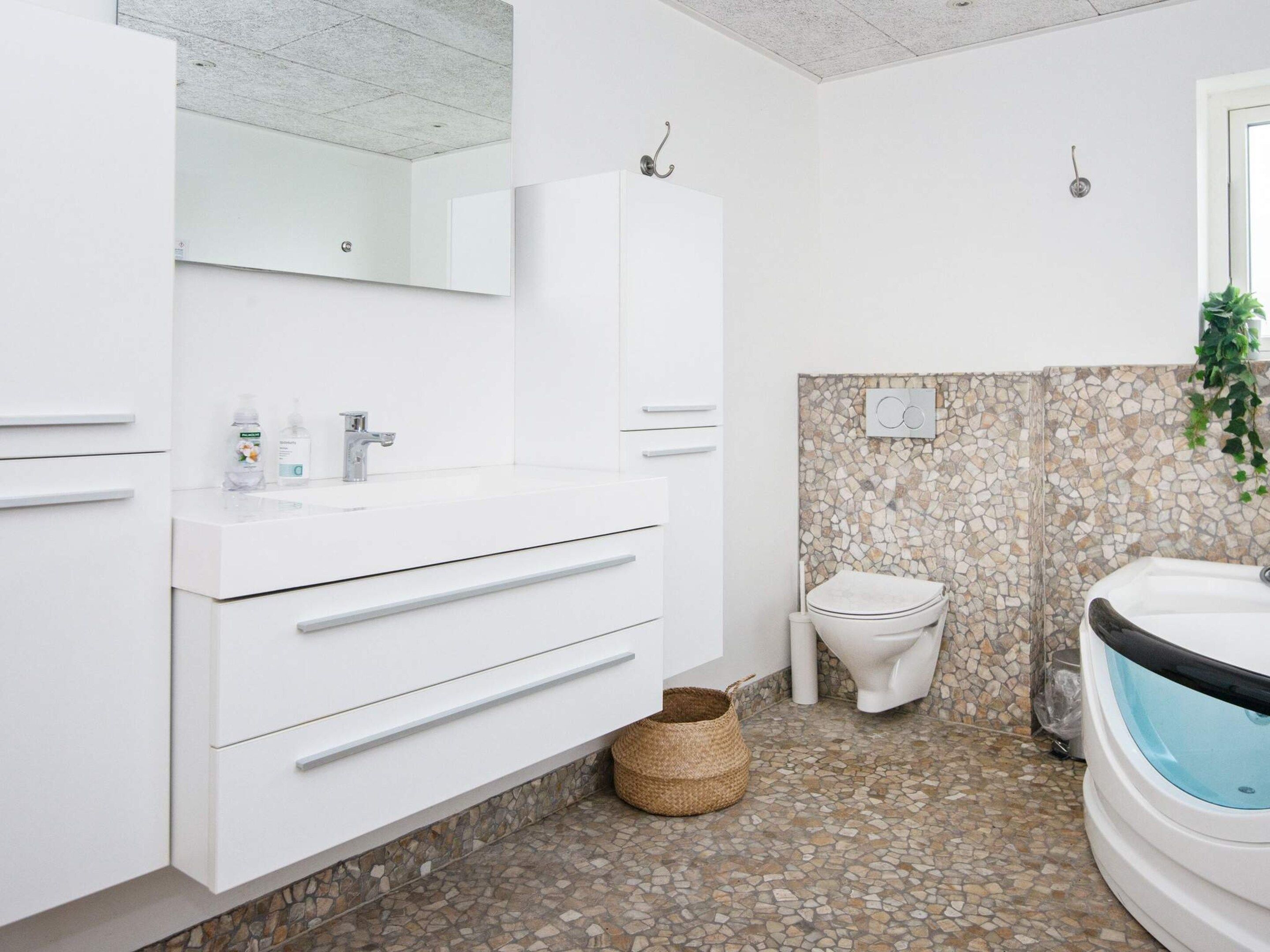 A modern bathroom with a white vanity, a toilet, and a bathtub.