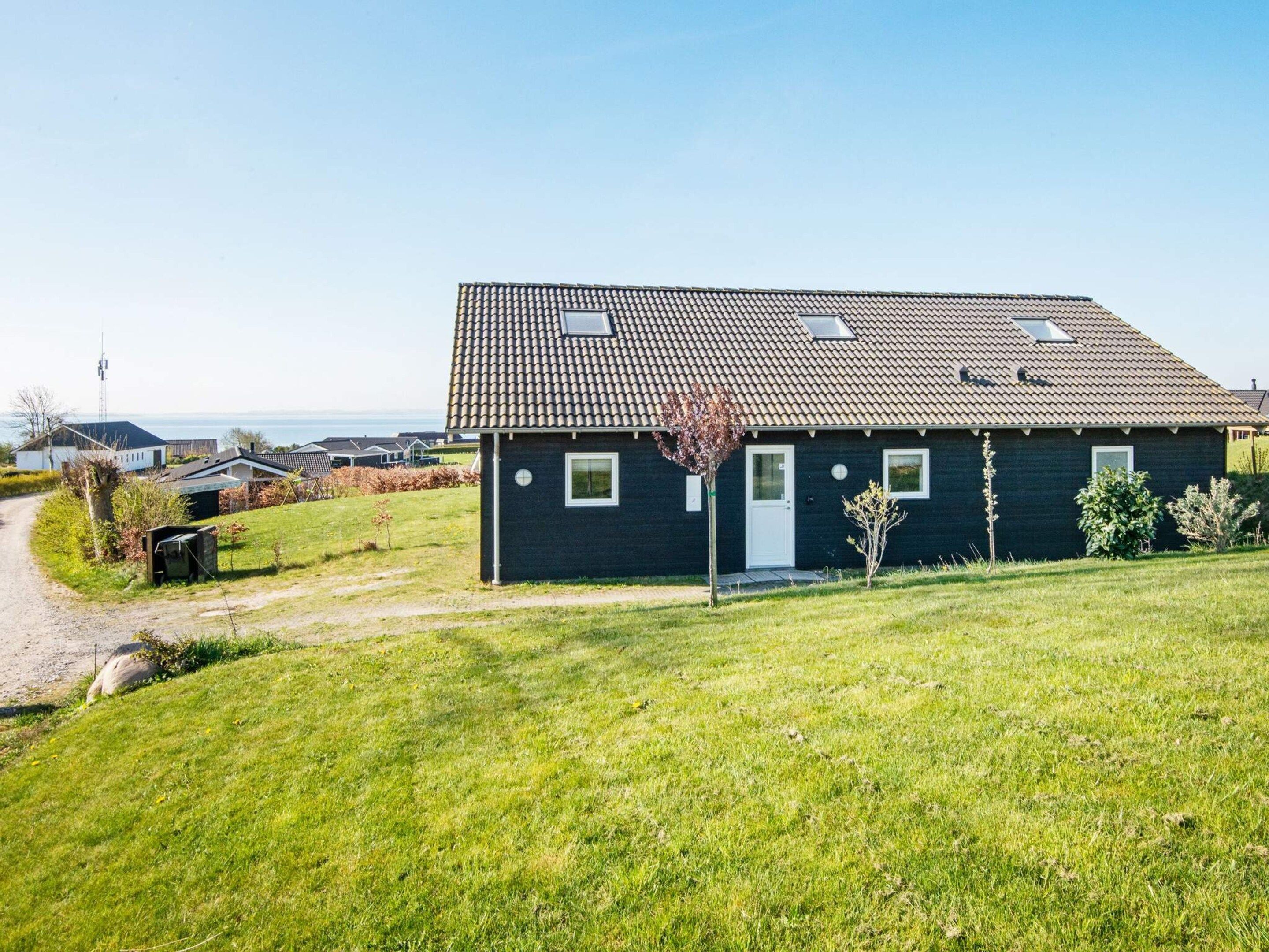 Une maison à deux étages, avec un toit en tuiles, une porte d’entrée et un petit jardin.