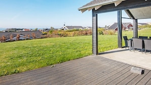 A covered outdoor seating area with a view of a residential neighborhood and a body of water. - 10 Person Holiday Home in Ronde (Ronde)