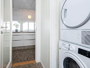A laundry room with a washing machine, a drying machine, and a small window with a plant.