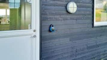 Una puerta con un panel de vidrio y un dispositivo de seguridad redondo y azul en la pared.