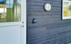 A door with a glass panel and a round, blue security device on the wall. - 10 Person Holiday Home in Ronde (Ronde)