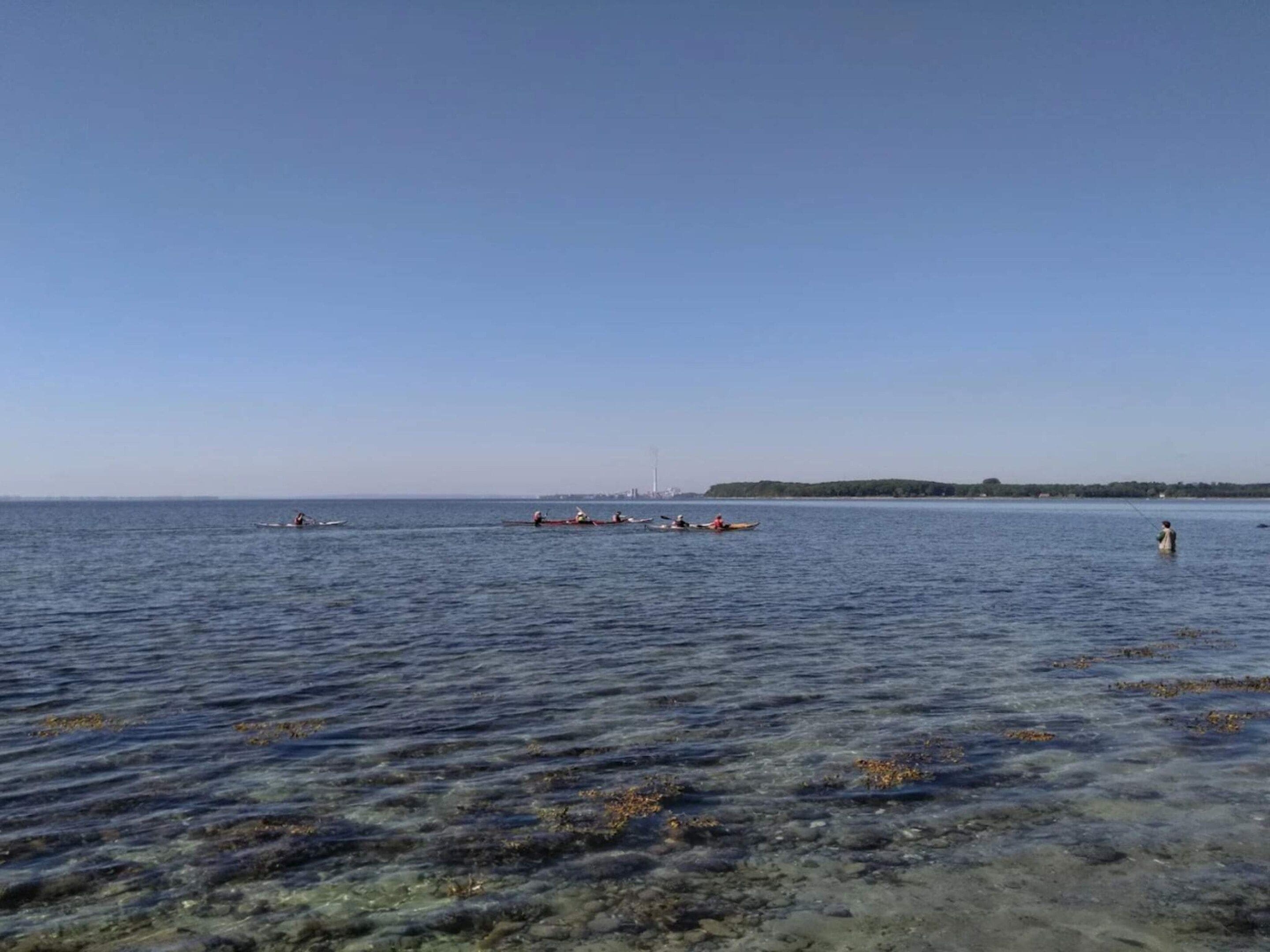A calm body of water with boats and a distant shoreline.
