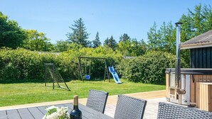 A patio with a table, chairs, a bottle of wine, and a glass. - 7 Person Holiday Home in Ulfborg (Ulfborg)