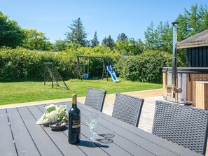A patio with a table, chairs, a bottle of wine, and a glass. - 7 Person Holiday Home in Ulfborg (Ulfborg)