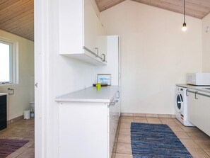 Une cuisine de taille réduite équipée d’un lave-linge, d’un four à micro-ondes et d’une petite fenêtre.
