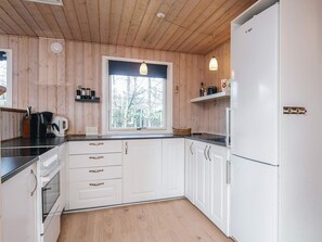 A kitchen with white cabinets, a window, and a refrigerator. - 7 Person Holiday Home in Ulfborg (Ulfborg)