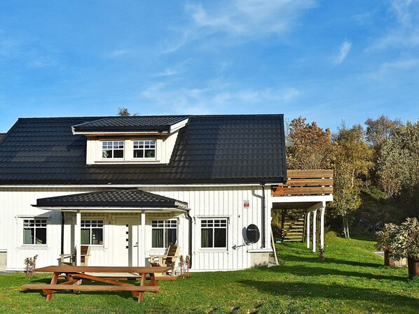 A two-story house with a covered porch, a satellite dish, and a picnic table.