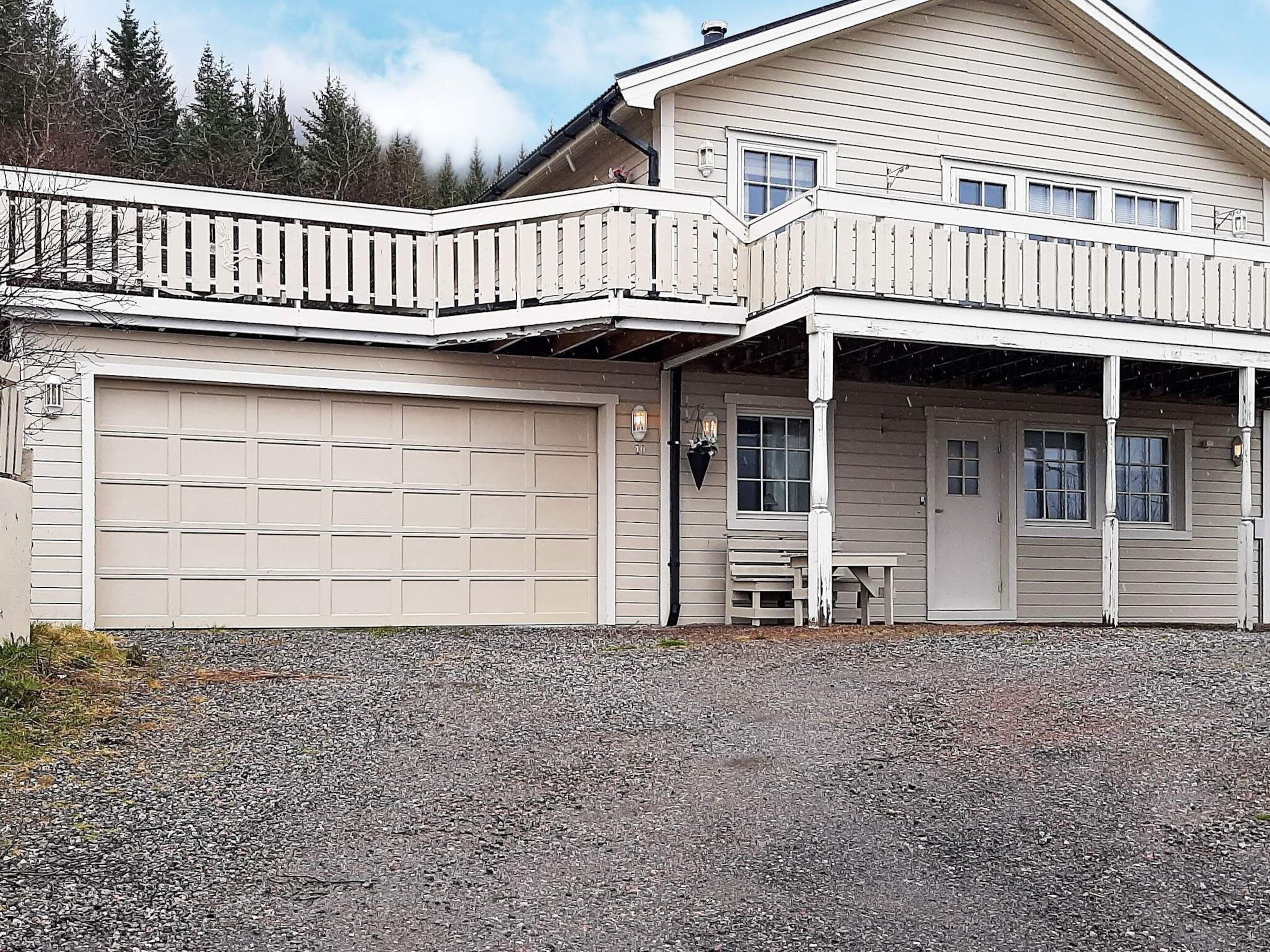 Een huis met twee verdiepingen, een garage, een overdekte veranda en een klein terras.