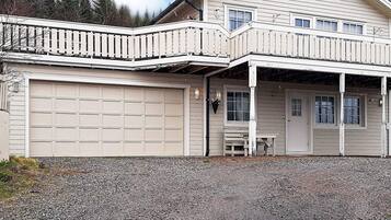 Een huis met twee verdiepingen, een garage, een overdekte veranda en een klein terras.