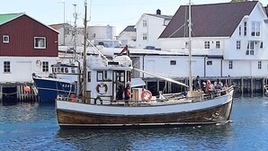 A wooden boat docked at a harbor with buildings in the background. - 4 Star Holiday Home in Sortland (Sortland)