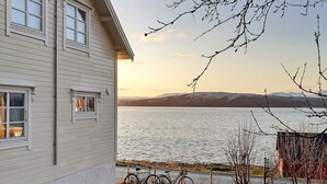 Une maison avec vue sur un lac et des montagnes en arrière-plan.