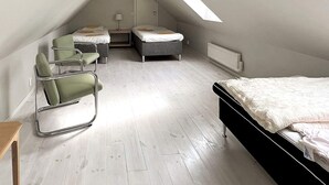 Et værelse med skrå vægge, en seng, to stole, et lille bord og en radiator.