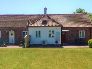 A two-story brick building with a tiled roof, a front door, and a small porch area with chairs. - 6 Person Holiday Home in Yngsjo, Sverige (Yngsjo)