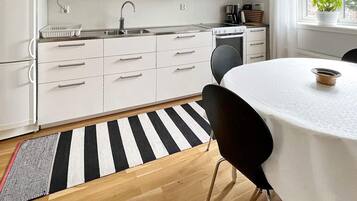 A modern kitchen with white cabinetry, a stainless steel sink, and a stove.