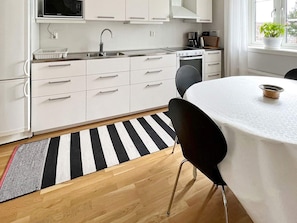Una cocina moderna con armarios blancos, un lavamanos de acero inoxidable y una estufa.