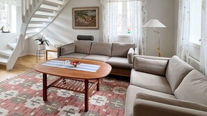 En stue med sofa, sofabord, lampe og trappe.