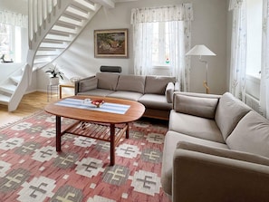 Una sala de estar con un sofá, una mesa de centro, una lámpara y una escalera.