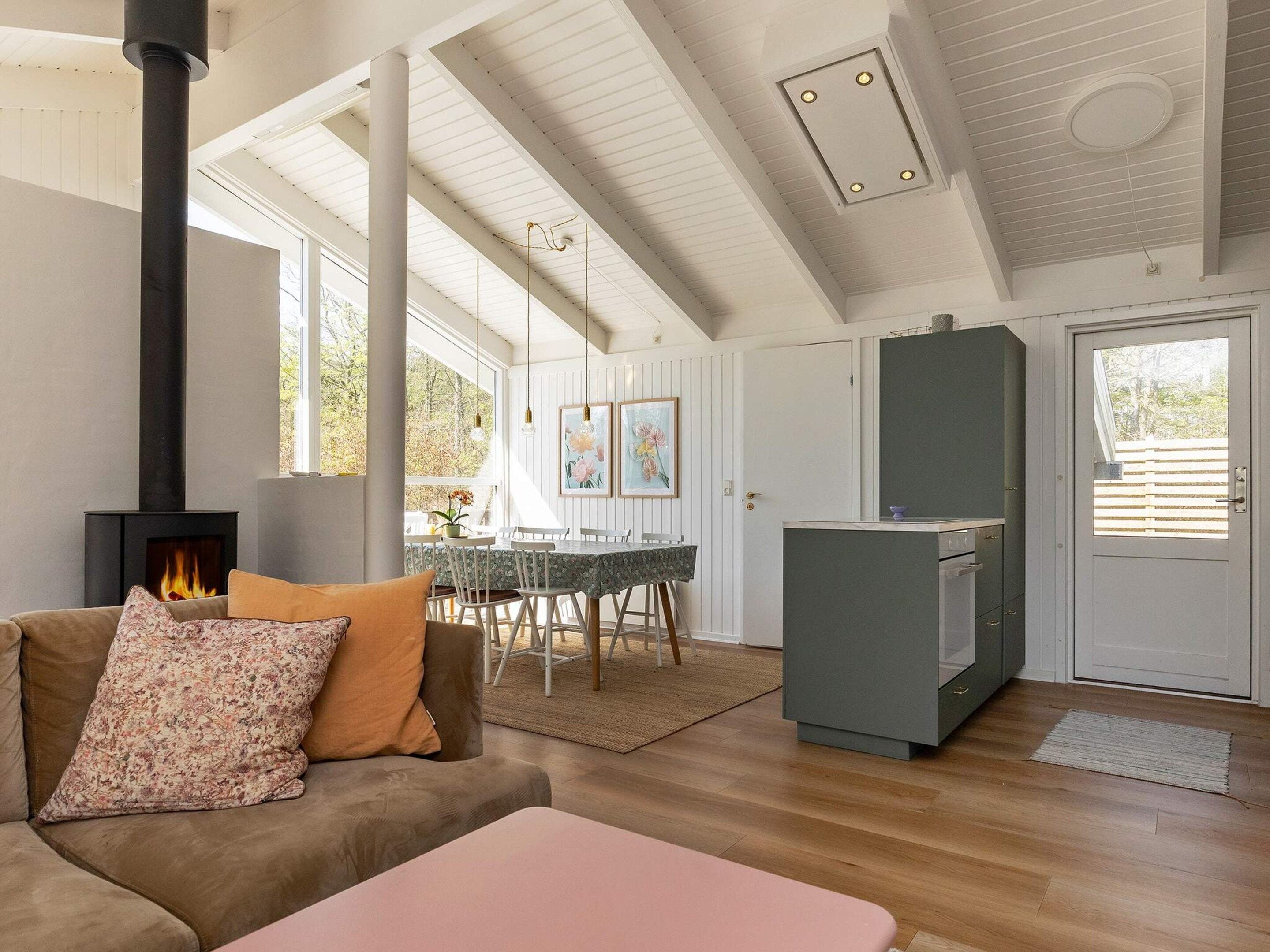 A cozy living room with a fireplace, a dining area, and a kitchen with a built-in oven.