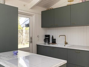 A kitchen with grey cabinets, a white countertop, a coffee maker, and a sink with a gold faucet. - 8 Person Holiday Home in Hals (Hals)