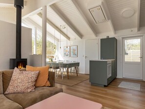 A modern living room with a fireplace, a dining area, and a kitchen.