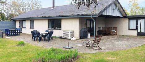 A single-story building with a covered patio area, outdoor seating, and a chimney.
