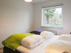 A bedroom with a bed, a window, and a view of trees outside.