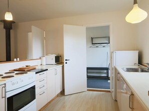 Una cocina compacta con estufa, microondas y fregadero.