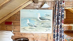 A rustic room with a wooden ceiling, a framed seagull painting, a red book, a brass lamp, and a woven mat. - 11 Person Holiday Home in Davik-by Traum (Bremanger)