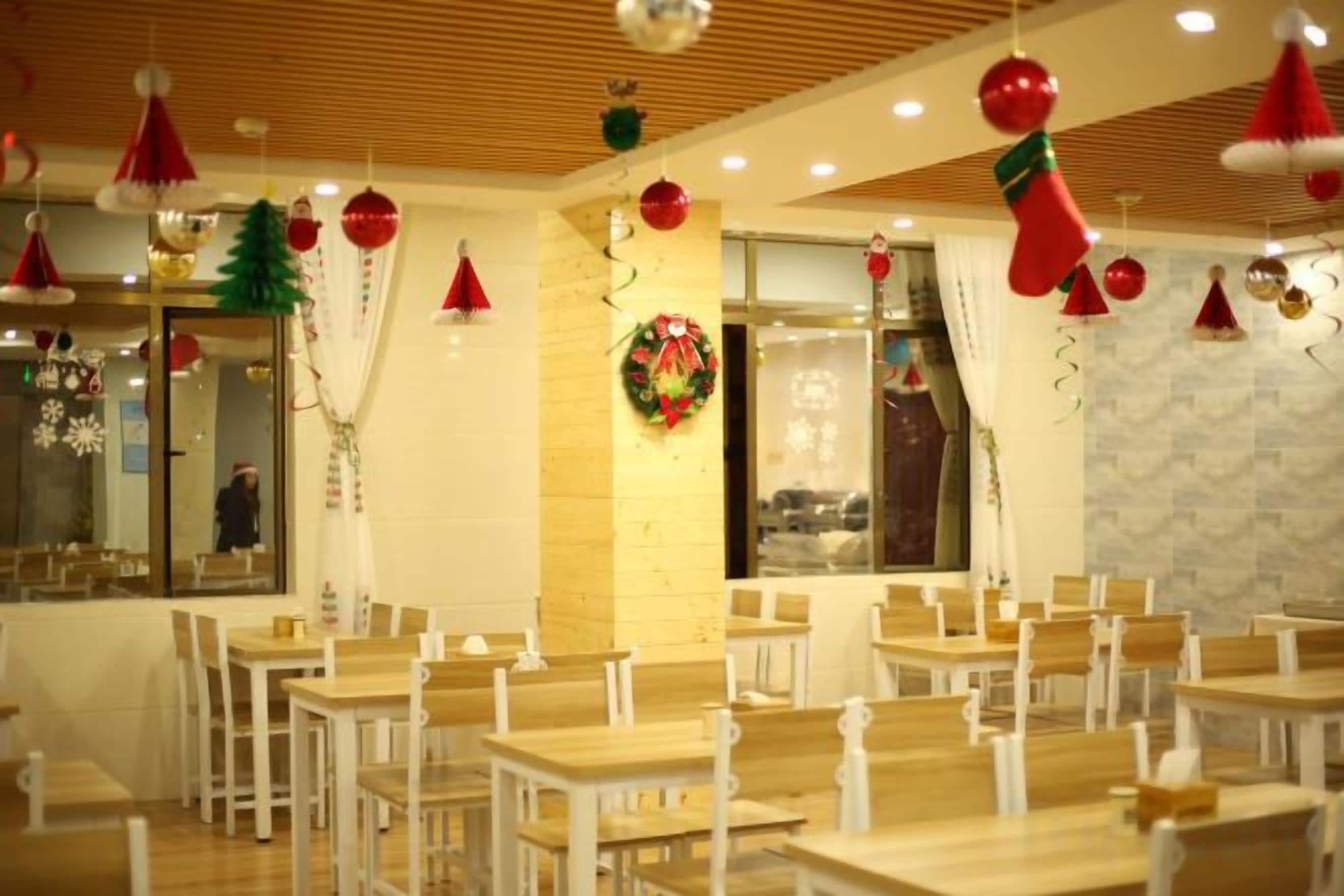 A dining area with multiple tables and chairs, a brick wall, and festive decorations.