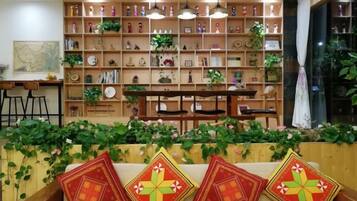A room with a wooden bookshelf, a dining table, and a sofa with decorative pillows.