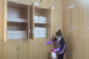 Une personne range des serviettes pliées dans un meuble en bois muni d’étiquettes.