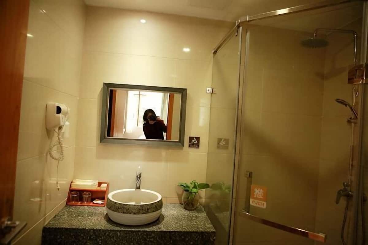 Un baño con lavamanos, espejo, ducha y secamanos.