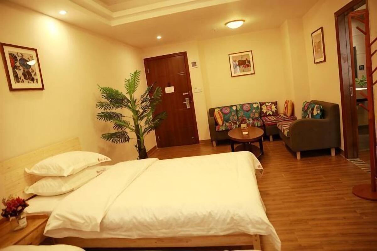 Una habitación de hotel con una cama, un sofá, una mesita y una planta.