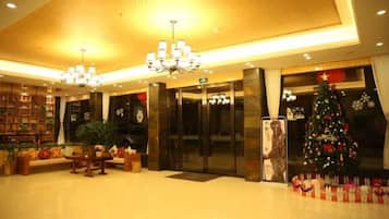 A lobby with a reception desk, a Christmas tree, and a large chandelier.