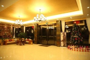 Un hall d’entrée avec un comptoir de réception, un sapin de Noël et un grand lustre.