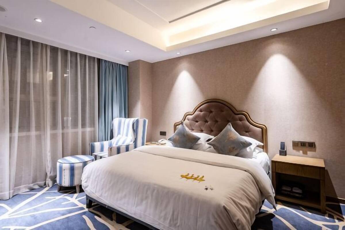 A hotel room with a large bed, a chair, a bedside table, and a nightstand.