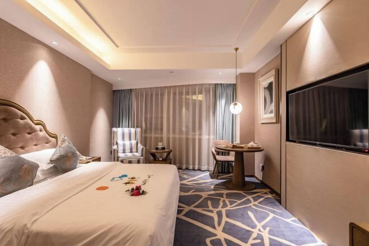 A hotel room with a large bed, a TV, a desk, and a chair.