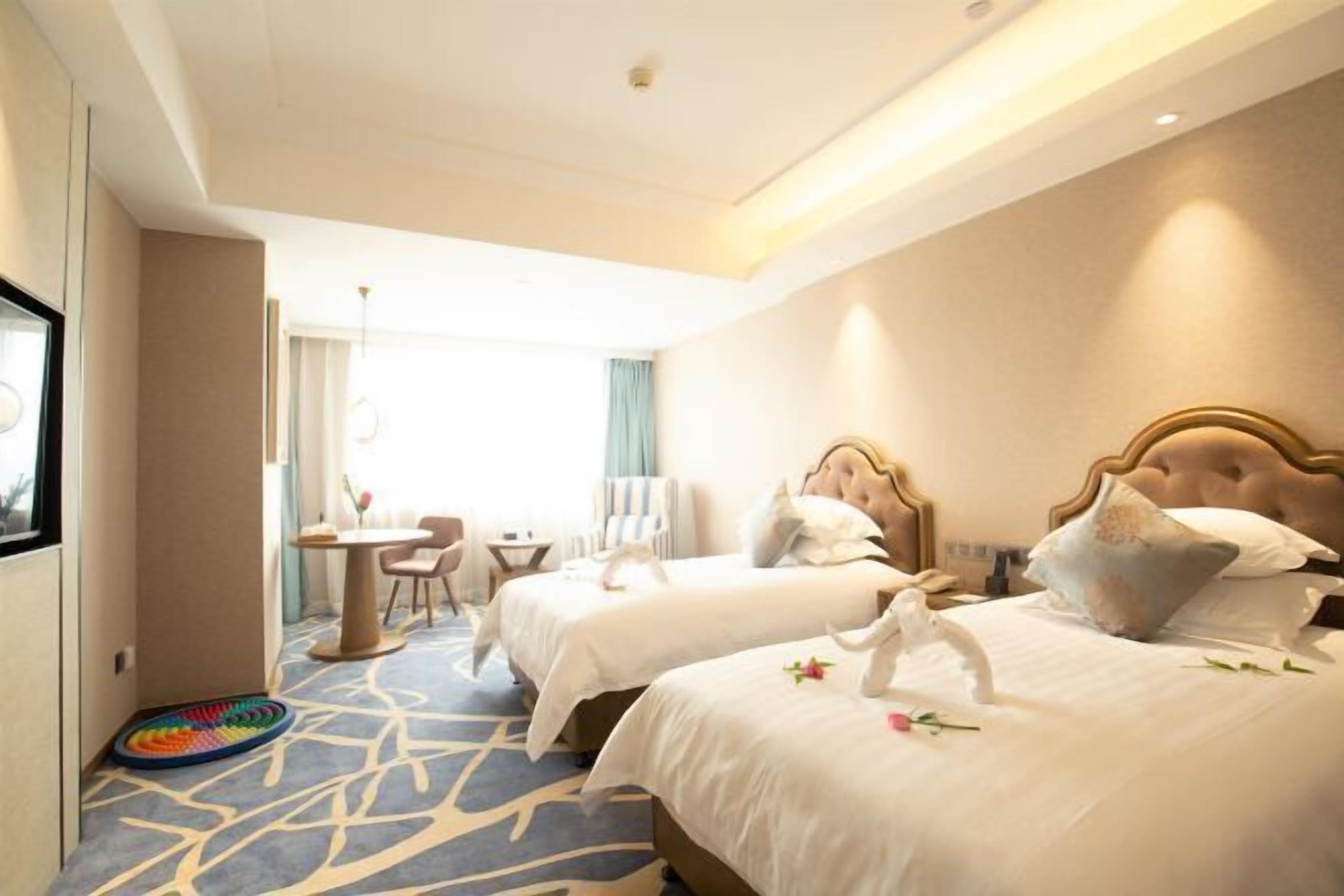 A hotel room with two beds, a small table, and a chair.