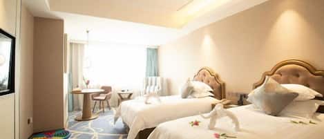 A hotel room with two beds, a small table, and a chair.