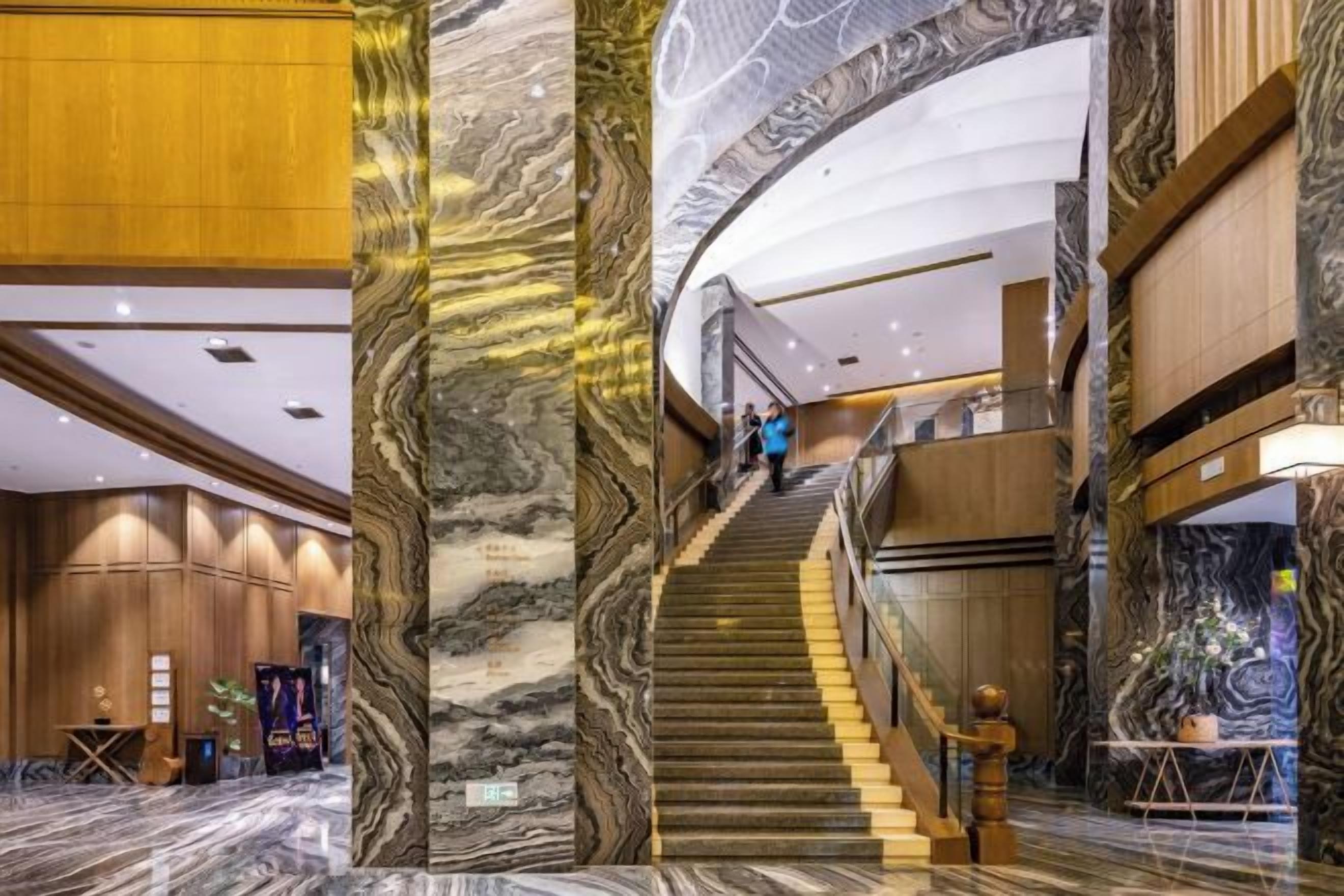 A grand staircase with marble columns, a reception area with wooden paneling, and a curved ceiling.