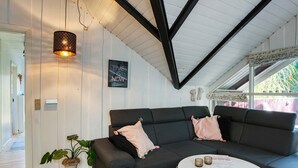 A modern living room with a dark grey sofa, a white coffee table, and a hanging light fixture. - 6 Person Holiday Home in Vaeggerlose (Vaeggerlose)