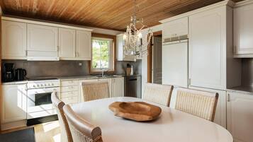 A kitchen with white cabinets, a stove, and a dining table with chairs.